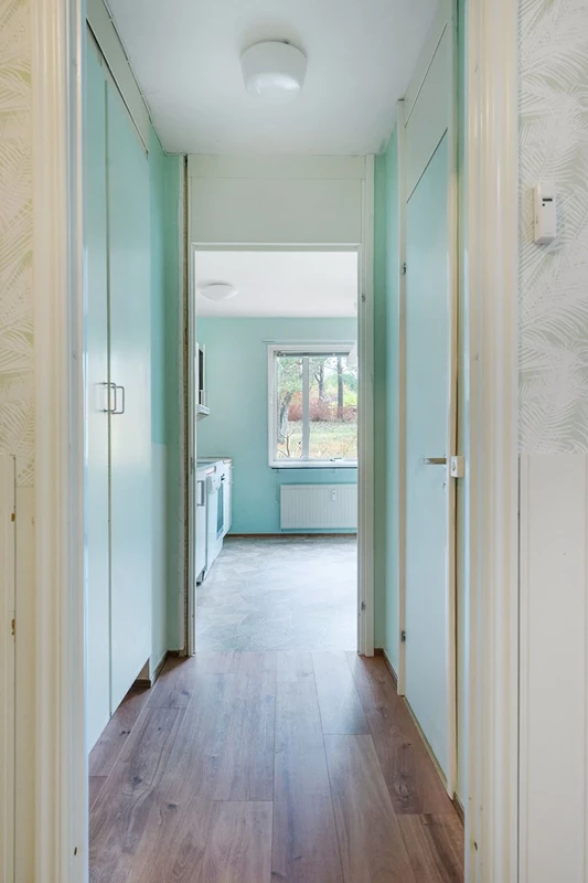 Liten hall mellan kök och entré, med förråd till höger i bild