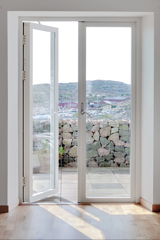 Stora dubbeldörrar mot en uteplats som sträcker sig runt huset