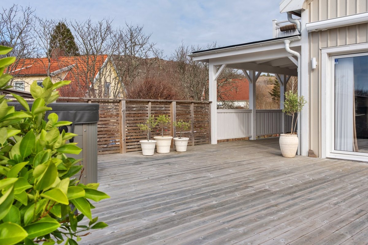 Stor solig altan som nås från kök, matsal och hall