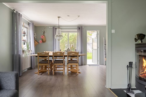 Matsal och vardagsrum i öppen planlösning med värmande kamin